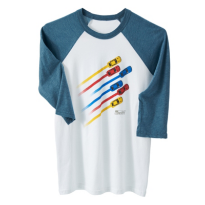 A white and blue 3 quarter length raglan sleeve t-shirt with a graphic design of five colorful race cars in motion, each leaving a streak of color behind them. The cars are red, yellow, and blue.