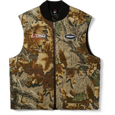 A camouflage vest with a black collar and front zipper. It has two chest logos ""TRD"" on the right and""HUF"" on the left