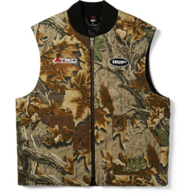 A camouflage vest with a black collar and front zipper. It has two chest logos ""TRD"" on the right and""HUF"" on the left