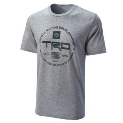 A gray T-shirt with a circular logo in dark green featuring 'Toyota Racing Development,' 'TRD,' and 'USA Motorsports Brand.