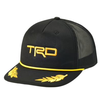 A black trucker hat with a mesh back and a solid front panel. The front of the hat features the letters 'TRD' embroidered in gold thread. There is a gold rope detail across the base of the front panel.