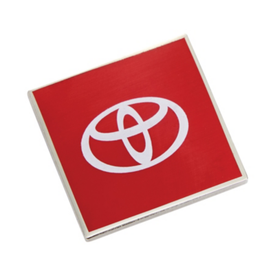 A pin shaped as a square red badge with a white Toyota logo in the center. 