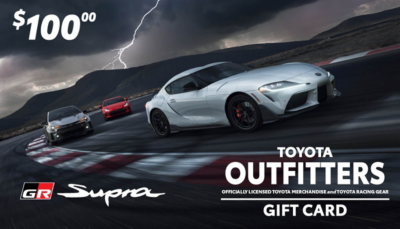 $100 Toyota Outfitters gift card with three Toyota Supra cars racing. Stormy sky background. Text reads 'Toyota Outfitters' and 'Officially licensed Toyota merchandise and Toyota racing gear.' GR Supra logo.
