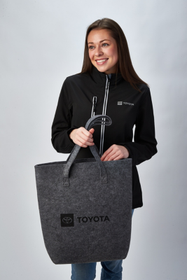 Person in black Toyota jacket holding grey Toyota tote bag