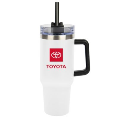 A white travel mug with a black handle and a clear lid featuring a black straw. The mug has the Toyota logo with the word ""TOYOTA"" written below in red