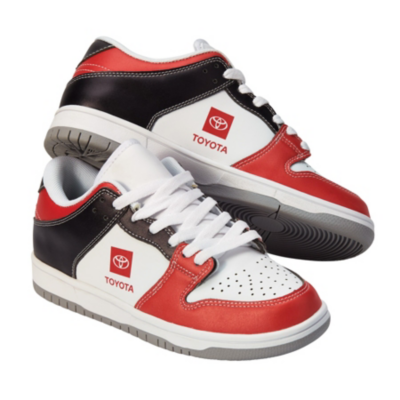 A pair of low-top sneakers with a white base, red and black accents, and the Toyota logo on the sides. The shoes have white laces and grey soles.