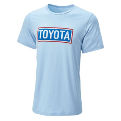 A light blue short-sleeve T-shirt with the word 'TOYOTA' printed in bold letters inside a rectangular box on the chest. The text is white with a red outline, and the box has a blue border.