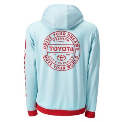 Back view of a light blue hoodie with red accents on the cuffs and hem. The back features a large circular red logo with the phrases 'DRIVE YOUR DREAMS,' 'PREMIUM QUALITY,' 'TOYOTA,' 'LET'S GO PLACES' with a small Toyota logo, and 'MOVE YOUR WORLD.'