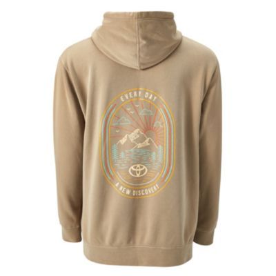 Back view of a beige hoodie featuring a colorful graphic of mountains, trees, a river, and a rising or setting sun. The design includes the phrase 'EVERY DAY A NEW DISCOVERY' and a Toyota logo at the bottom.