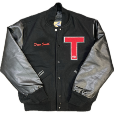 A black varsity jacket with leather sleeves, a red letter 'T' on the left chest