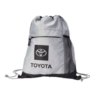 A gray drawstring backpack with a black front pocket featuring the Toyota logo and the word 'TOYOTA' printed below it. The backpack has black mesh side pockets and black drawstrings