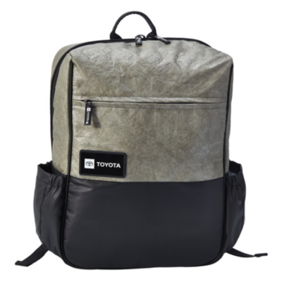 A gray and black backpack with a front zippered pocket, Toyota logo patch, side pockets, and adjustable shoulder straps