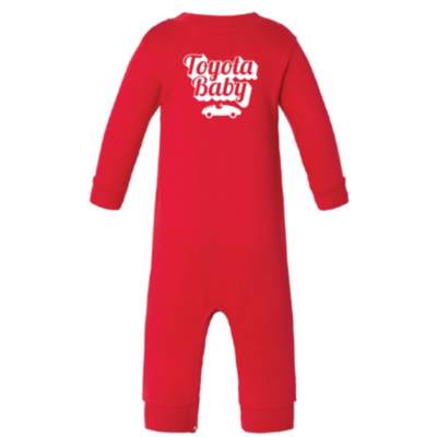 A red baby onesie with long sleeves and legs. The back of the onesie features white text that reads Toyota Baby above a small white car graphic