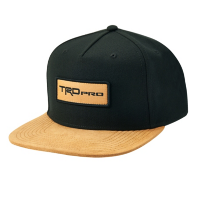 A black snapback hat with a flat brim that is tan in color. The front of the hat features a rectangular patch with the text ""TRD Pro"" embroidered in black on a tan background