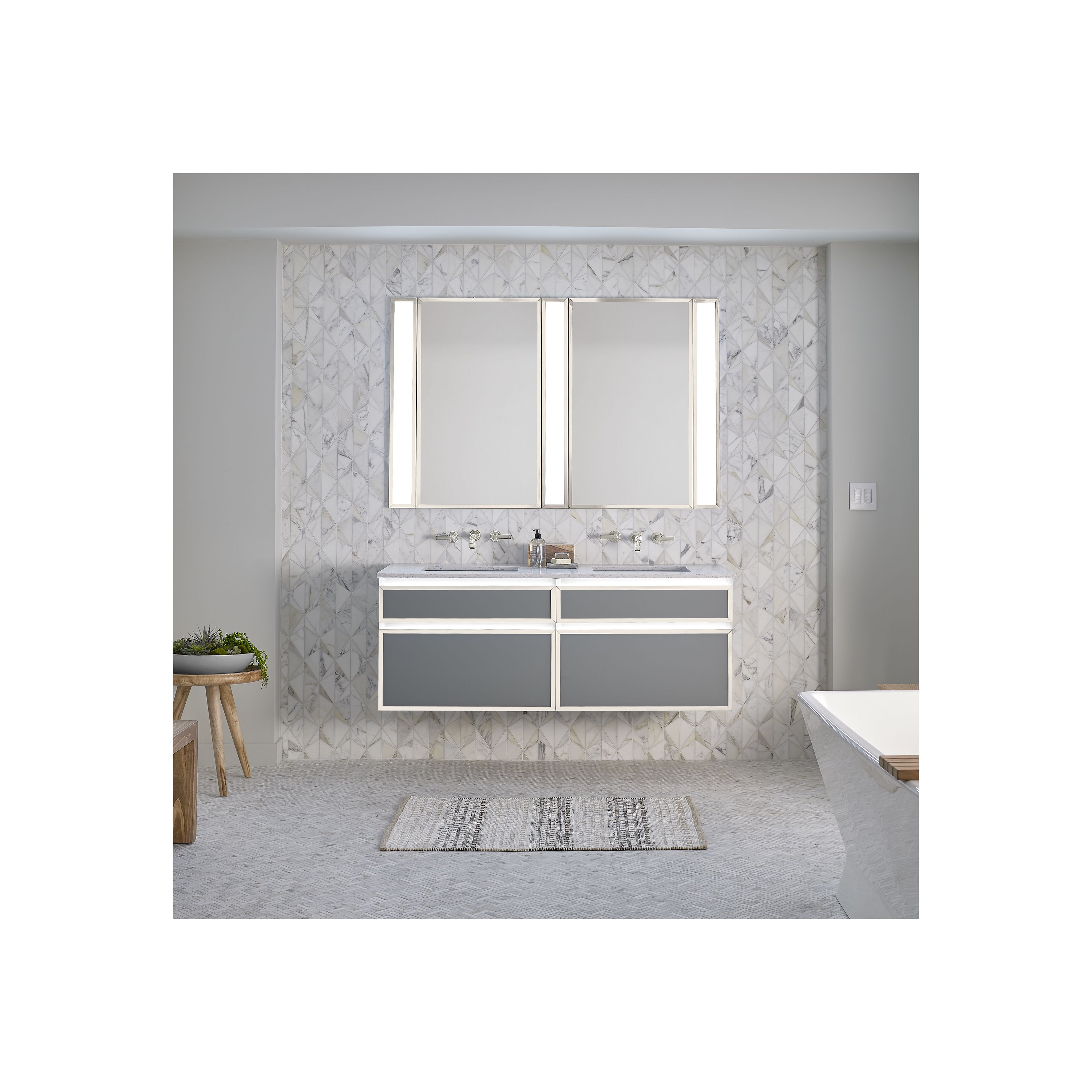 Bathroom vanity with white cabinets and mirrored wall.