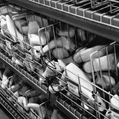 Metal shelves filled with white plastic lasts used for manufacturing boots.