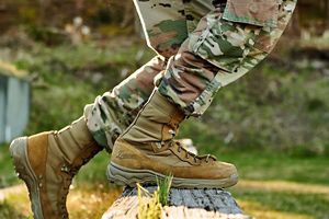 a woman steps over an obstacle in a pair of coyote colored military boots