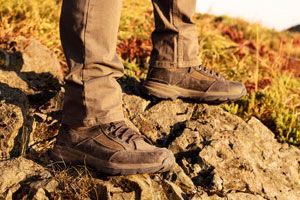 a man laces up a pair of brown hunting boots with a moc toe design