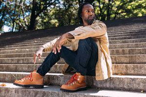 a man laces up a pair of brown suede boots