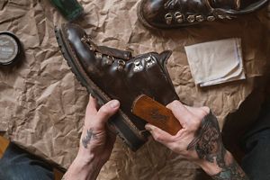 a man laces up a pair of brown hunting boots with a moc toe design