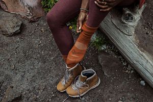 a man laces up a pair of brown hunting boots with a moc toe design