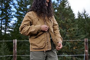 a man laces up a pair of brown hunting boots with a moc toe design