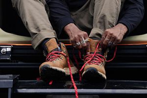a man laces up a pair of brown suede boots