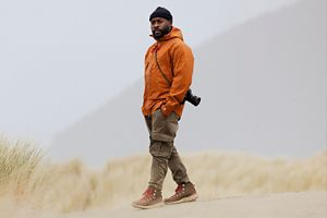 a pair of brown work boots with orange laces caked in mud