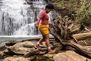 a man hikes against the backdrop of alpine lake wearing brown and red hiking boots