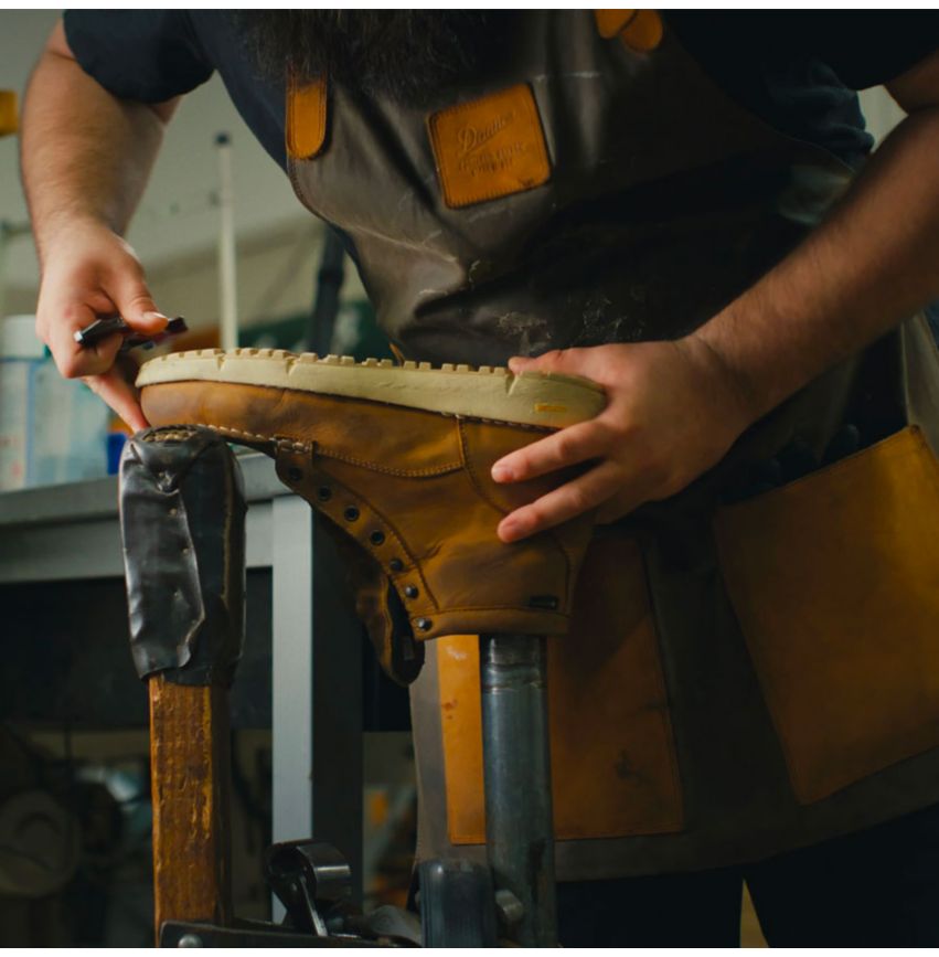 A man is using a computer to design a pair of Danner Boots.