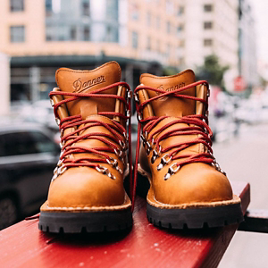 a pair of brown work boots with orange accents