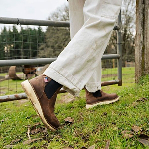 a pair of brown work boots with orange accents