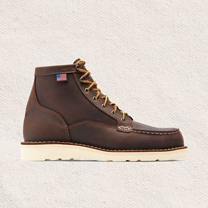 a man laces up a pair of brown hunting boots with a moc toe design