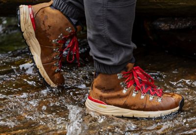 Lower body view of hiker walking on wet rocky terrain