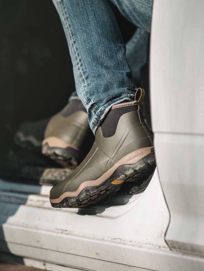 A stone colored pair of ankle high rubber boots is shown getting into a vehicle