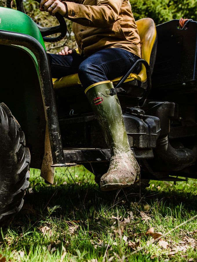 A stone colored pair of ankle high rubber boots is shown getting into a vehicle