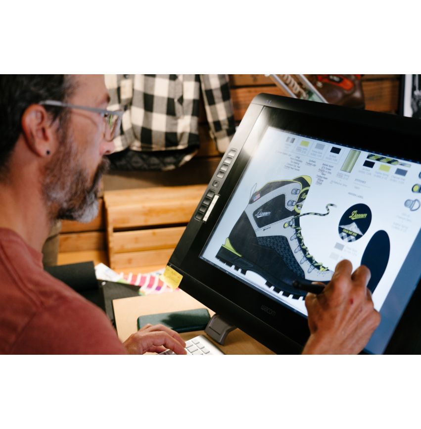 A man is using a computer to design a pair of Danner Boots.
