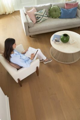 a woman writing in a notebook in a chair, which is on top of a wood floor