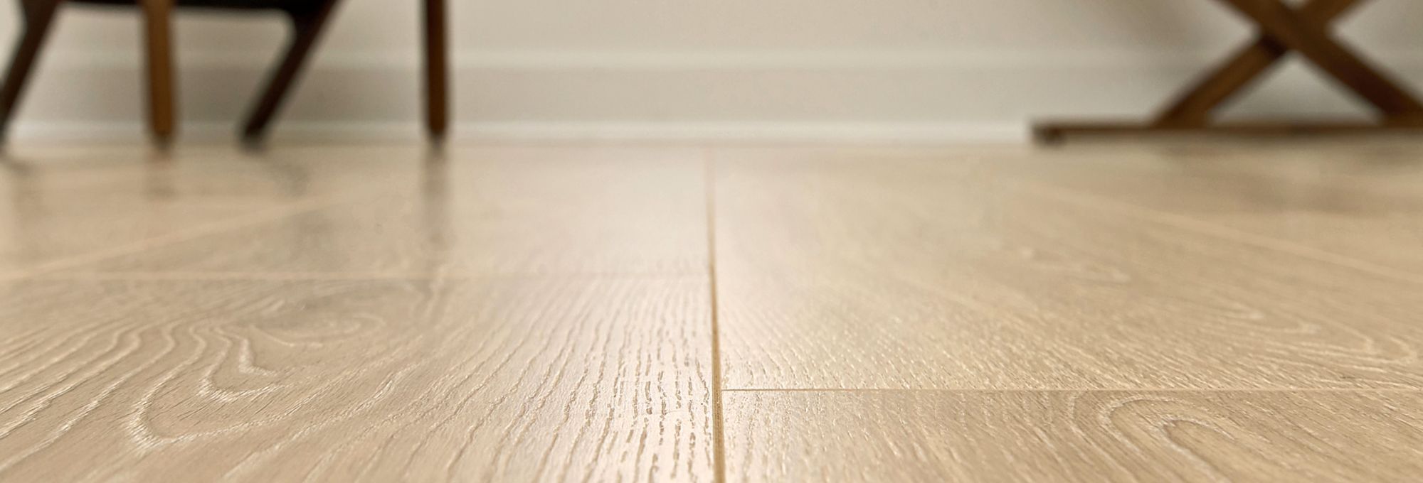 Close up of brown hardwood flooring with chairs in the distance