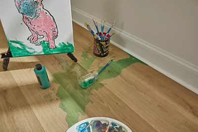 Easel with dog painting on hardwood floor with a paint cup spill onto the waterproof floor in front of it