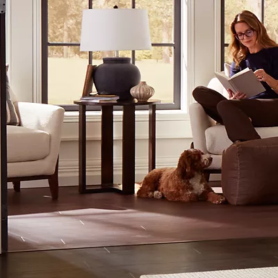 Woman reading in her book nook in her bedroom with dark wood waterproof flooring