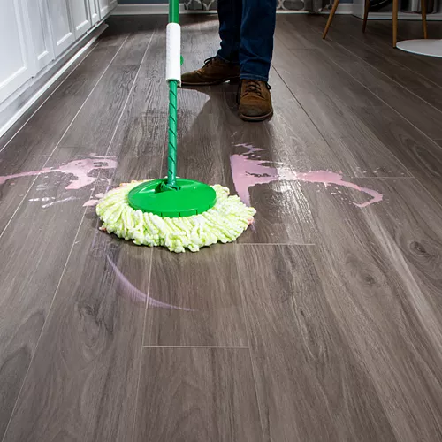 cleaning pink spill on hardwood floor with a green mop