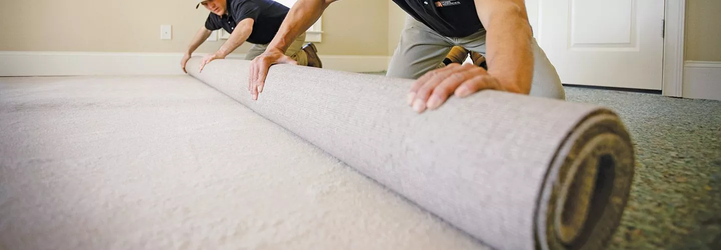 2 men installing a carpet roll