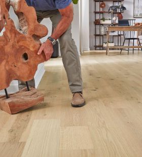 man moving a sculpture on hardwood floors