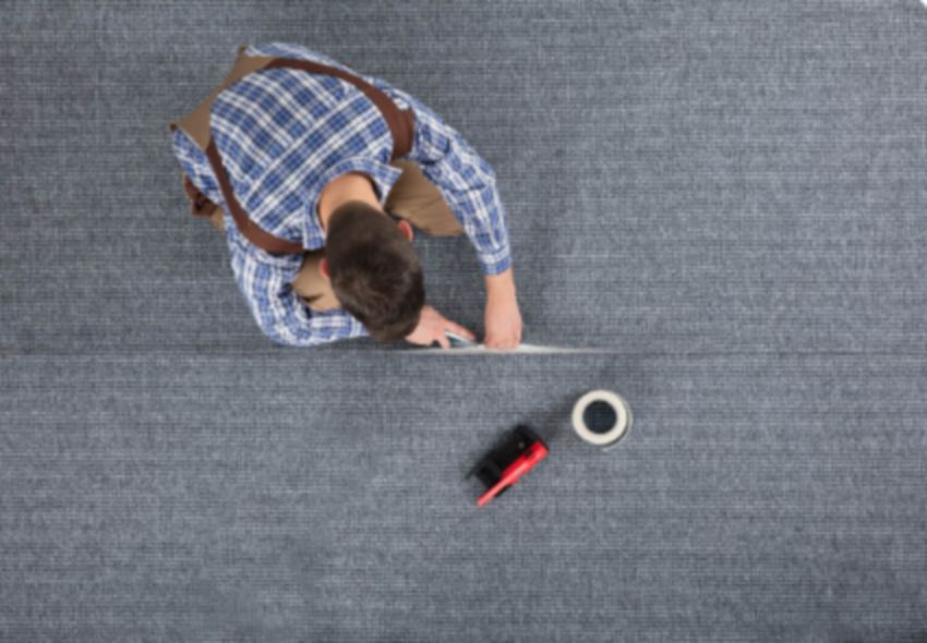 Worker installing carpet flooring
