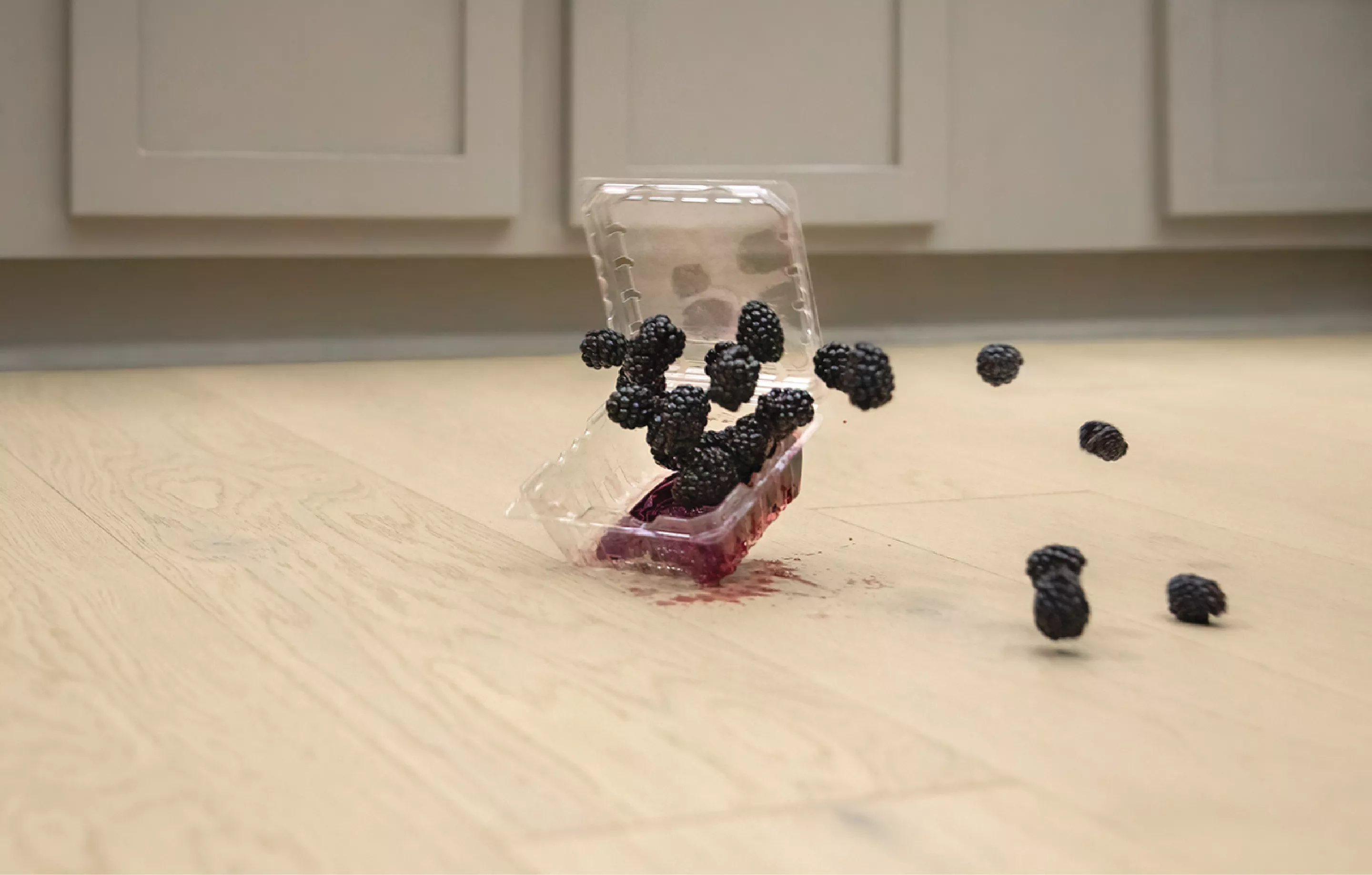 A Spilled Container of Berries on a Hardwood Floor