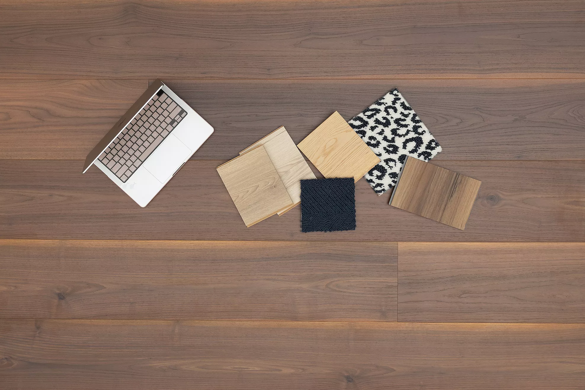 A computer and other flooring samples on top of a hardwood floor
