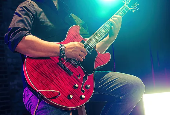 musician holding red electric guitar