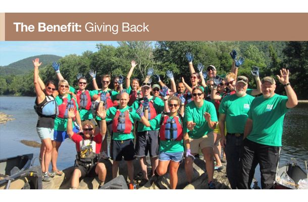 he Benefit: Giving Back; Image: Happy employees waving at the camera during a river rafting trip